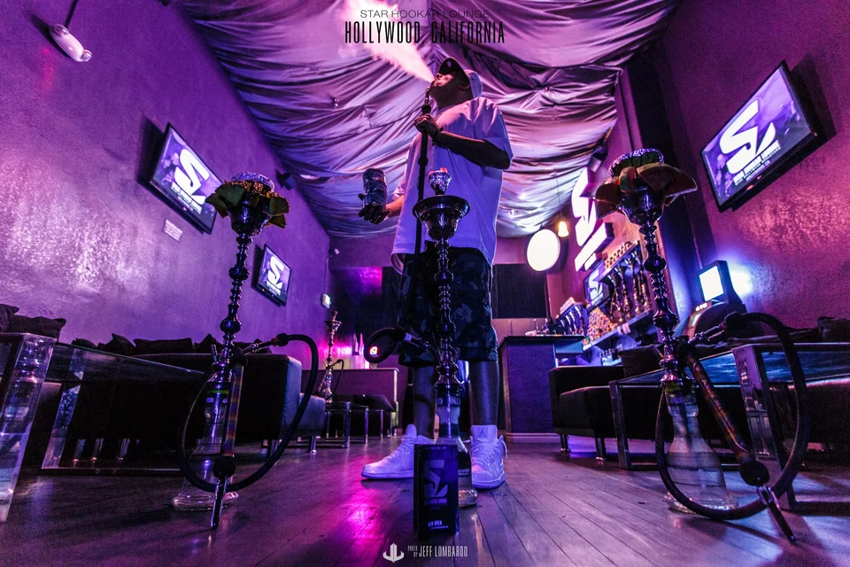 Smoking hookah beneath Star’s purple draped ceiling, surrounded by fruit bowl hookahs